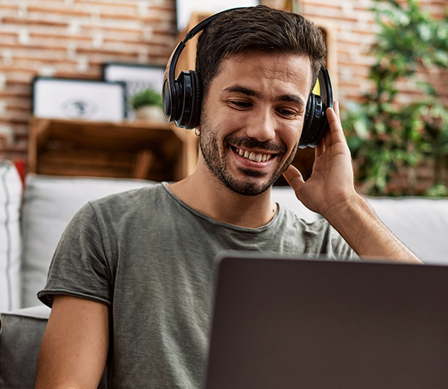 Confident young woman in headphones using laptop while sitting at her working place Confident young woman in headphones using laptop while sitting at her working place